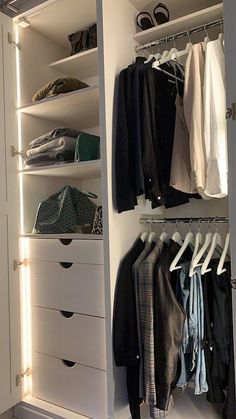 an organized closet with white drawers and clothes hanging on the rails, including sweaters