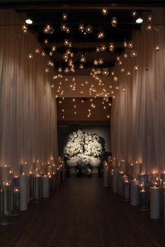 a room filled with lots of white candles and lights hanging from it's ceiling