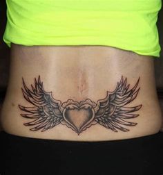 a woman's stomach with wings and a heart tattoo on the side of her stomach