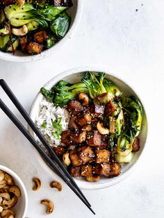 two bowls filled with food next to chopsticks on a white counter top,