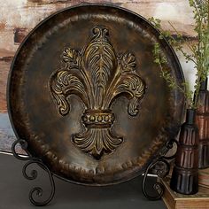 a metal plate with a fleur de lis design on it sitting next to some vases