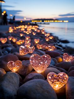 lighted hearts are lined up on the rocks by the water