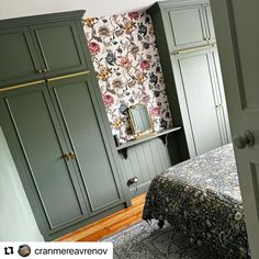 a bedroom with green cupboards and floral wallpaper on the walls, along with a bed