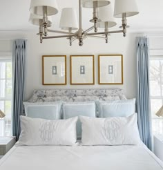 two framed pictures hang above the bed in this white and blue bedroom with matching drapes