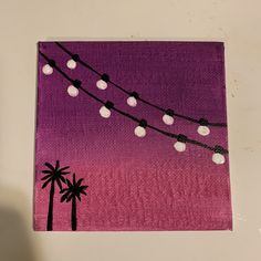 a purple and black painting with white balls hanging from it's sides, next to a palm tree