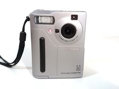 a silver digital camera sitting on top of a white table next to a black cord