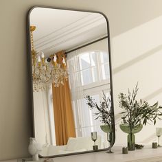 a mirror sitting on top of a mantle next to a vase