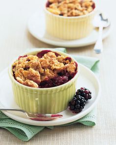 two small dishes filled with berries and crumbled oatmeal on plates