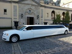 a white stretch limo parked in front of a large stone building with columns and windows