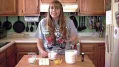 a woman standing in front of a kitchen counter with two cups on top of it