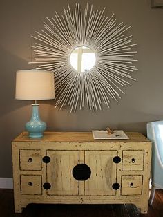 a white dresser sitting next to a lamp on top of a table