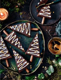 some brownies with white frosting on top of a plate next to two cups