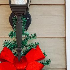 a lamp post with a red bow hanging from it's side on a house