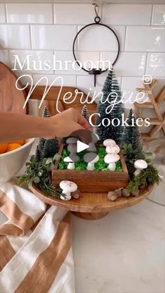 someone is decorating a tray with mushrooms and greenery on it for christmas cookies