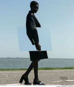 a woman walking down the street with a large piece of glass on her head and legs