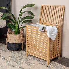 a wooden storage box sitting next to a potted plant on top of a rug