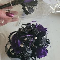 a purple and black corsage is being held by a woman's hand