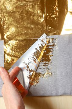 a person is using a paintbrush on a piece of paper that has been painted gold