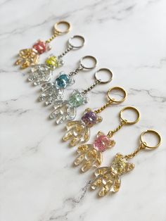 six key chains with different colors and shapes on top of a marble countertop in the shape of teddy bears