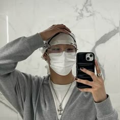 a woman wearing a face mask while holding her cell phone in front of her head