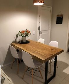 a wooden table with white chairs and a potted plant sitting on top of it