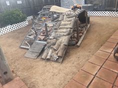 a pile of wood sitting on top of a dirt covered ground next to a fence