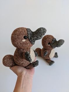 two stuffed animals sitting on top of each other in the palm of a person's hand