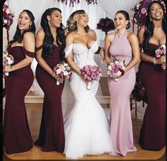 a group of women standing next to each other in front of a white wall holding bouquets