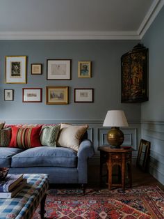 a living room filled with furniture and lots of framed pictures on the wall above it