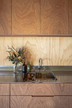 a kitchen with wooden cabinets and stainless steel counter tops is pictured in this image, there are vases filled with flowers on the sink