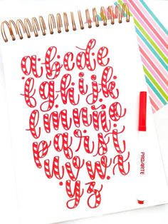 a spiral notebook with red lettering on it next to a pen and paper clipping