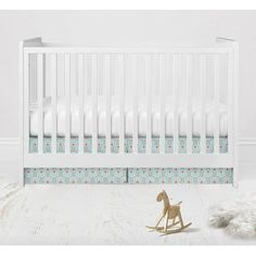 a white crib with a rocking horse next to it and a rug on the floor