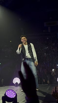 a man standing on top of a stage with his hands up in front of him