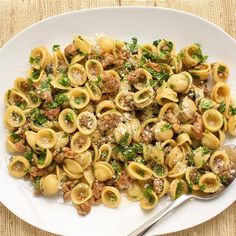 a white plate topped with pasta covered in meat and veggies next to a fork