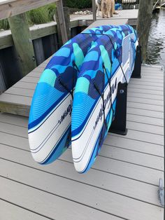 a blue and white surfboard sitting on top of a wooden dock