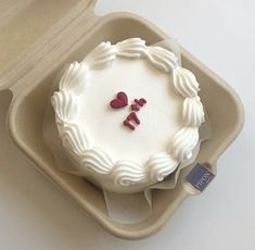 a white cake with two hearts on it in a box, ready to be eaten