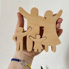 a hand holding a wooden cutout of a family with two children and one adult