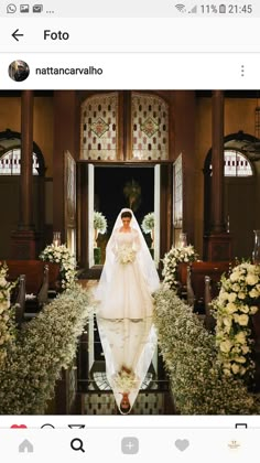 the bride is walking down the aisle in her wedding dress and veil with flowers on it