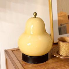 a yellow lamp sitting on top of a wooden table next to a bowl and hat