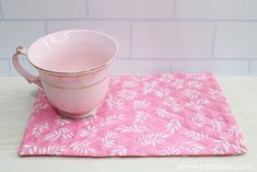 a pink coffee cup sitting on top of a place mat