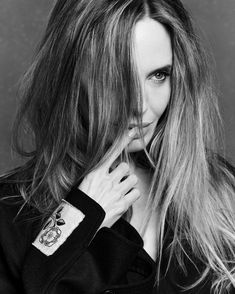 a black and white photo of a woman with long hair holding her hand to her face