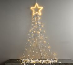 a lighted christmas tree with a star hanging from it's side on a table