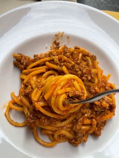 a white plate topped with spaghetti and meat