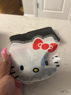 a hello kitty bag sitting on top of a counter next to a person's hand