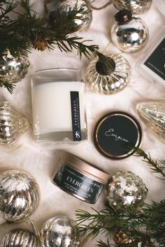 a candle and some ornaments on a white table with silver baubles around it