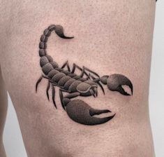 a black and white scorpion tattoo on the thigh