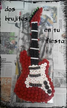 a red guitar made out of buttons on top of a newspaper page with the caption do's bruhtass en tu ages en fu fiesta fiesta fiesta fiesta fiesta