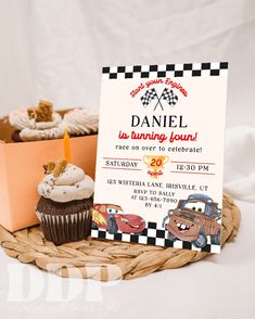 a birthday party with cars and cupcakes on a basket next to a sign