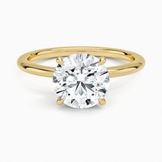 a yellow gold engagement ring with a round brilliant cut diamond in the center, on a white background