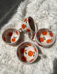 three oranges painted on the side of four cups